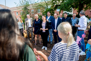 Die Ministerin Wiebke Osigus steht in einer Gruppe von Menschen. Im Vordergrund sind Kinder von hinten zu sehen, die eine selbstgebastelte Girlande halten. Die Ministerin lacht freundlich.