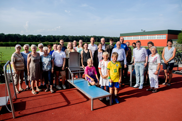 Eine Gruppe Menschen posiert um die Geräte des Bewegungsparkes für ein Gruppenfoto. Die Gruppe besteht aus Kindern, Erwachsenen und Senioren.