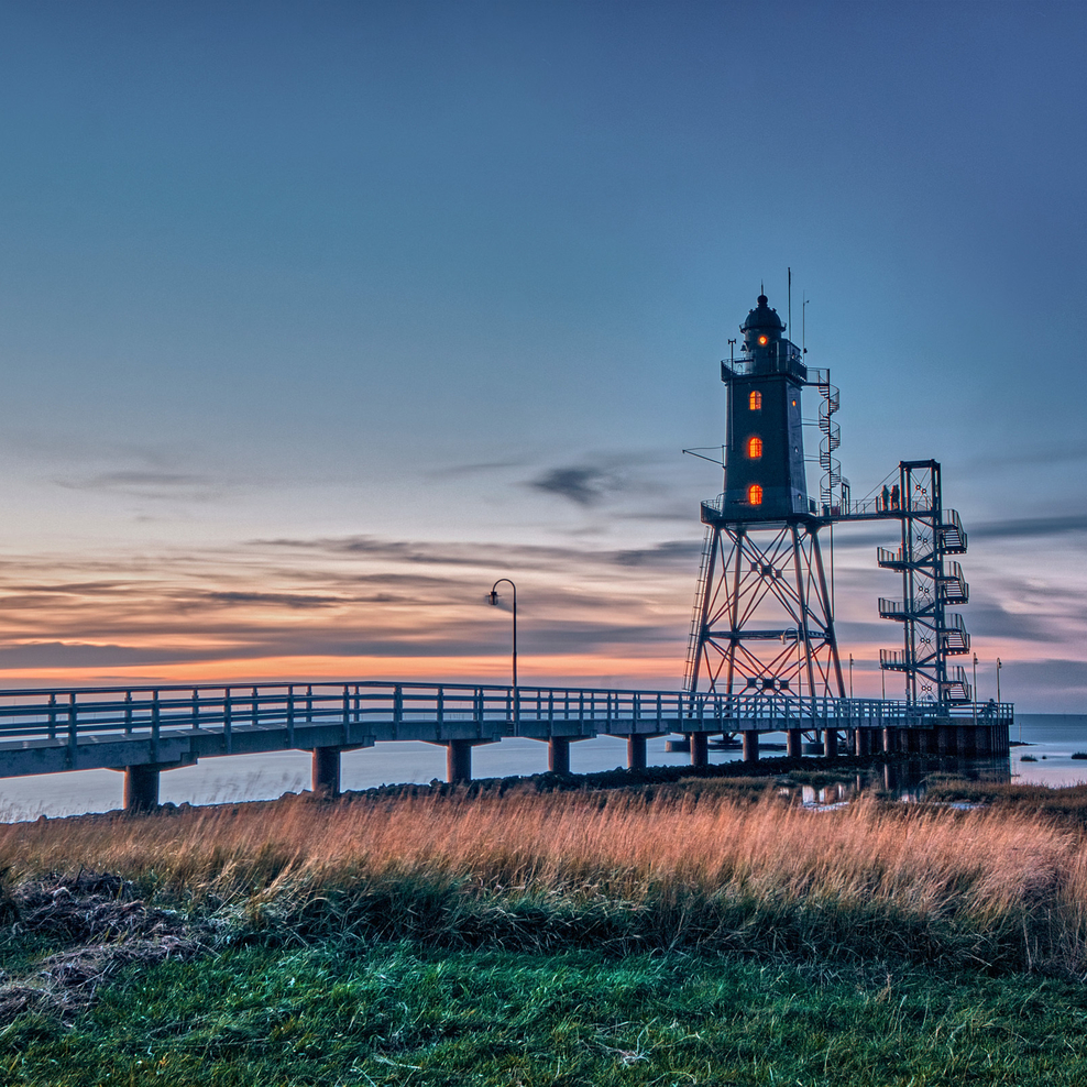 Leuchtturm und Steg im Sonnenuntergang