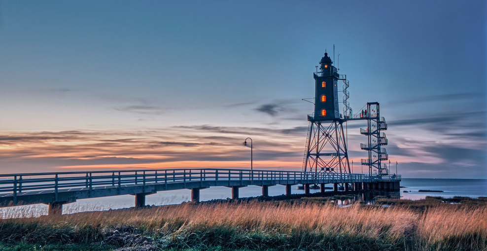 Leuchtturm und Steg im Sonnenuntergang